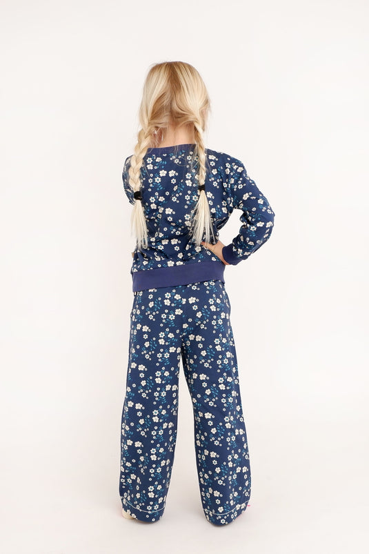 Back of a girl wearing retro organic wide leg trousers in dark blue with small white flowers for kids
