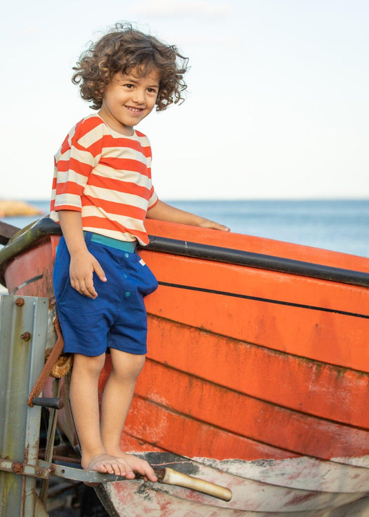 Boy wearing shorts in bright blue with breton stripe t-shirt