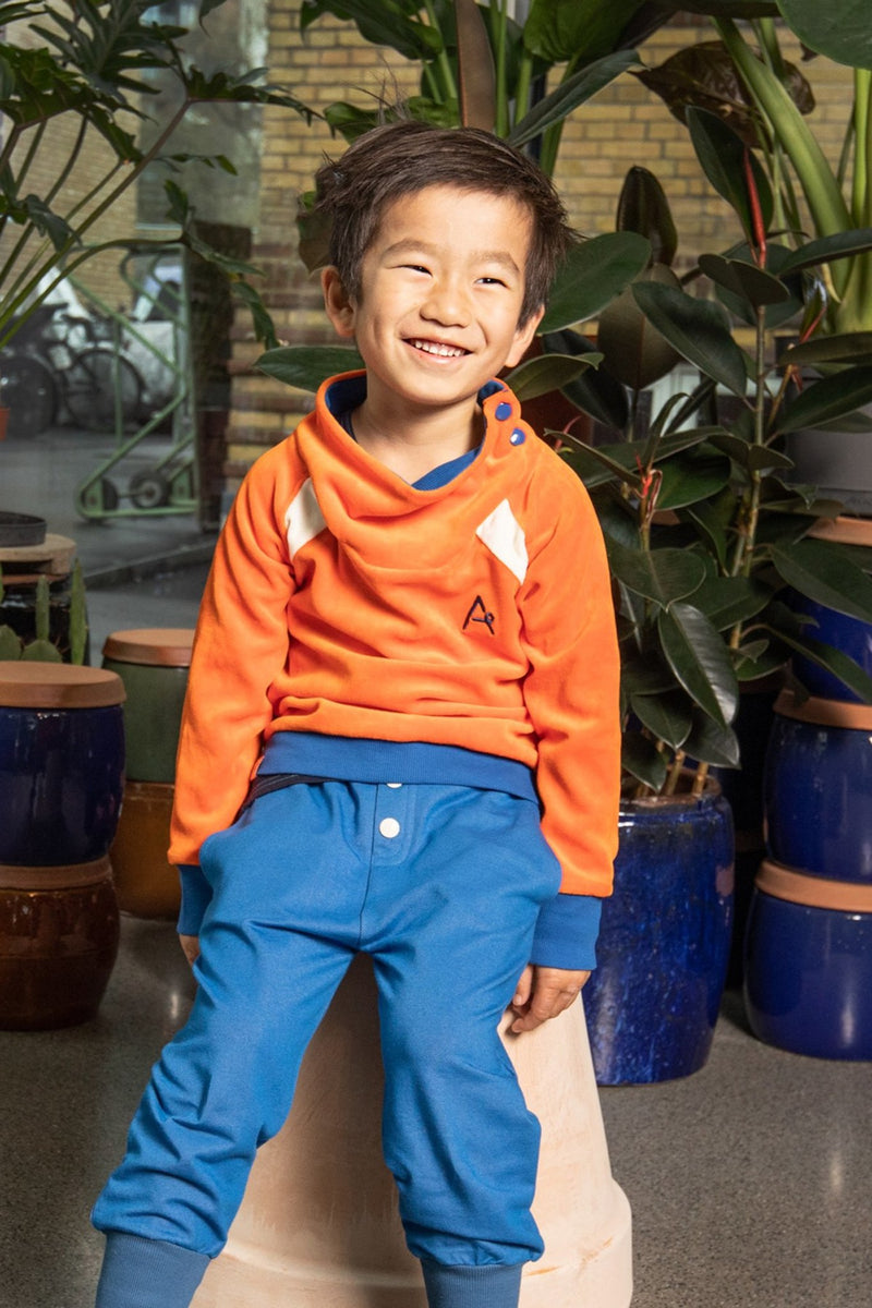 Load image into Gallery viewer, Child wearing button pants in bright blue for children in organic cotton
