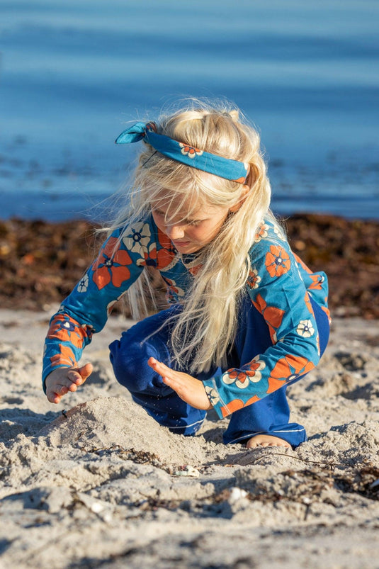Scandinavian girl wearing githa blouse in organic cotton for children in bright blue and orange flowers
