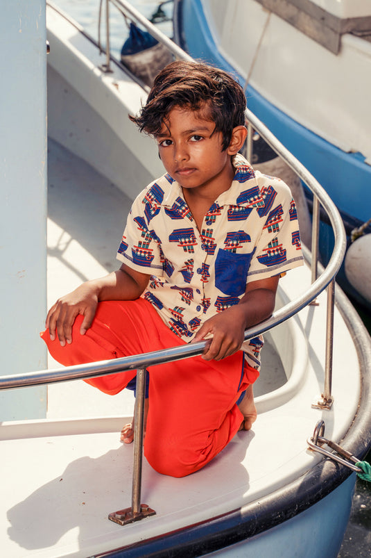 Child on a boat wearing Retro looking shirt for kids in white with blue ships