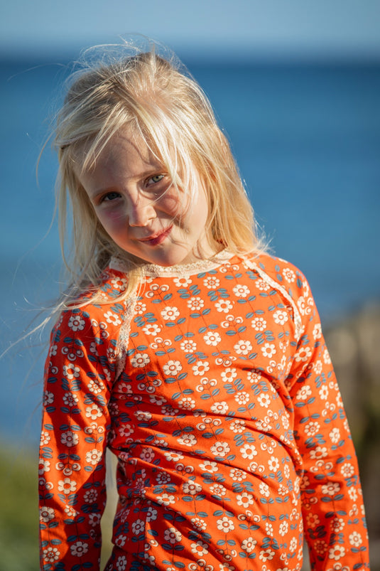 Danish girl wearing retro orange blouse with small white flowers in organic cotton for girls