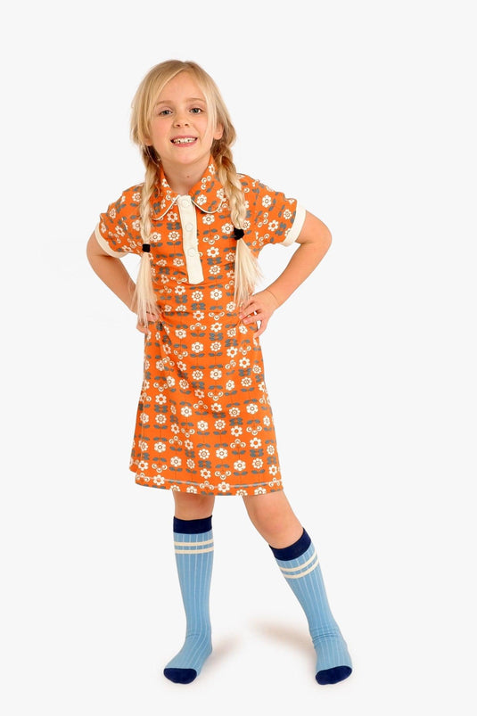 Small girl wearing the retro Julie dress in organic orange cotton with small flowers