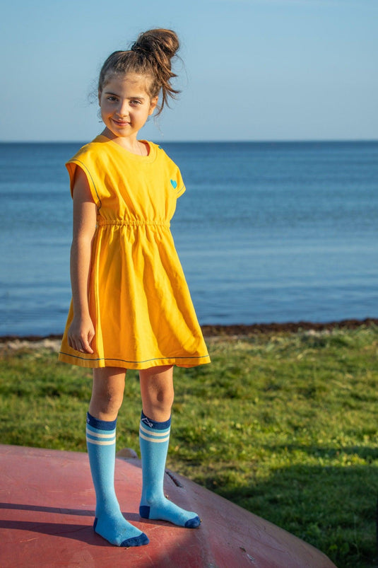 Scandinavian girl wearing a yellow retro dress with blue buttons in organic fabric by albaofdenmark