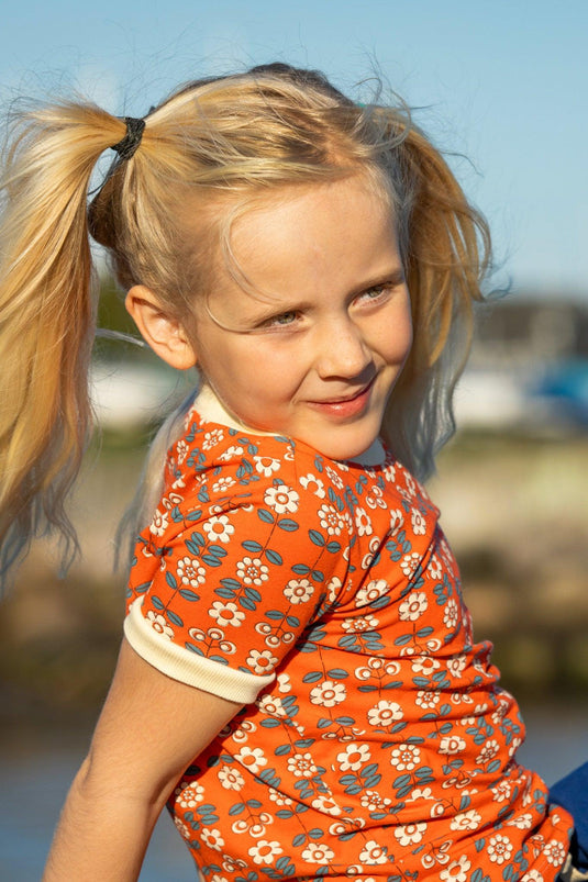 Blond girl wearing retro blouse for children in orange with flowers